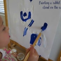 Painting a rabbit shaped cloud on the easel. Easel art inspired by Little Cloud by Eric Carle