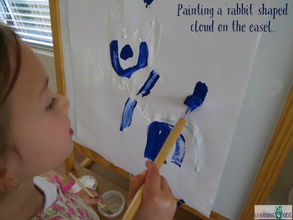 Painting a rabbit shaped cloud on the easel. Easel art inspired by Little Cloud by Eric Carle