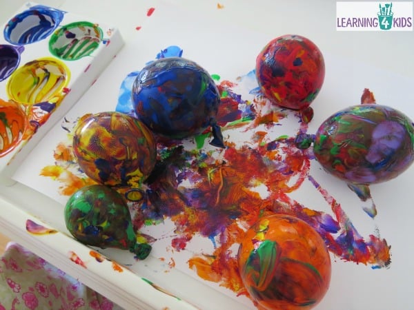 Painting with Balloons - rolling balloons around in paint on paper in a tray